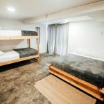 A minimalist bedroom design featuring bunk beds and a double bed with a cozy atmosphere.