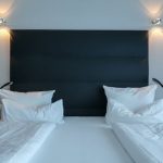 Elegant hotel bedroom featuring a neatly made double bed, modern lighting, and plush pillows.