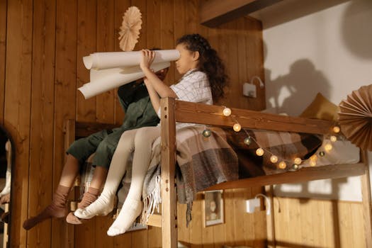 Two children playing with paper rolls on a decorated bunk bed in a wooden room.