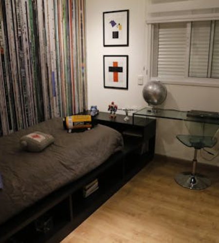 A sleek and stylish bedroom with a bed, glass desk, and modern art decor.
