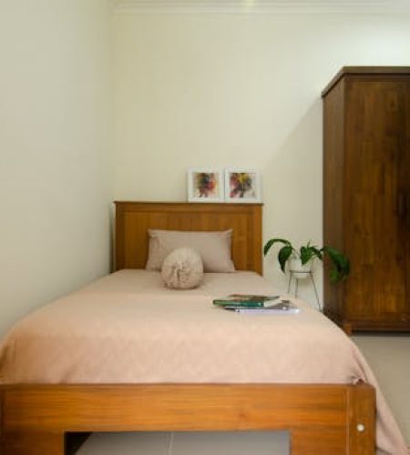 Cozy minimalist bedroom featuring wooden furniture and indoor plant.
